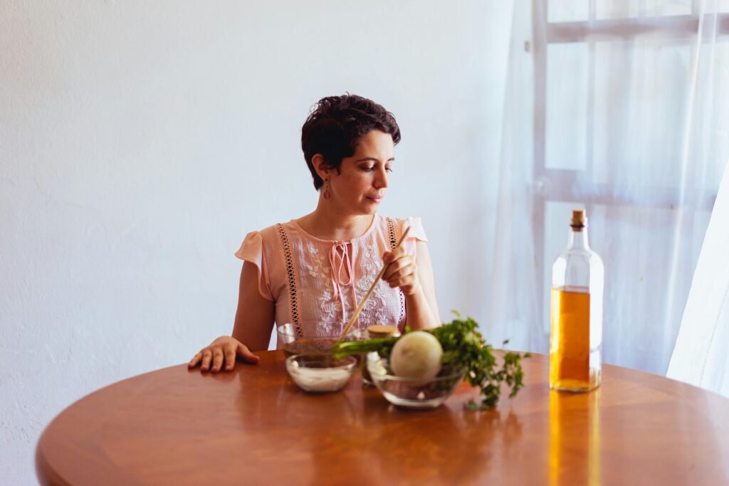 Mujer latina en perimenopausia preparando ingredientes frescos — vegetales, hierbas y aceite de oliva — como parte de una estrategia nutricional para el control metabólico