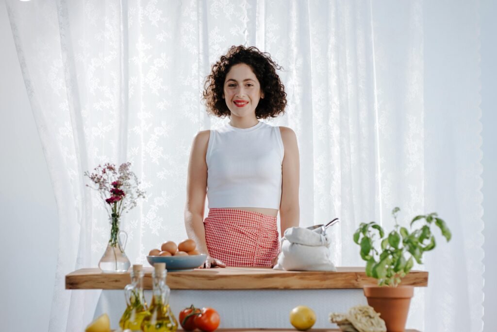 Mujer con SOMP frente a mesa con ingredientes de dieta mediterránea — aceite de oliva, vegetales frescos y hierbas para mejorar la resistencia a la insulina